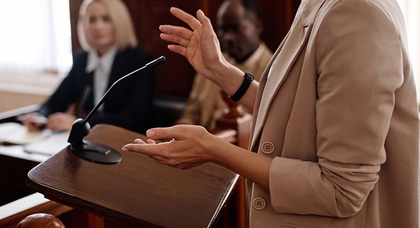 attorney-gesturing-while-speaking-at-a-hearing-table