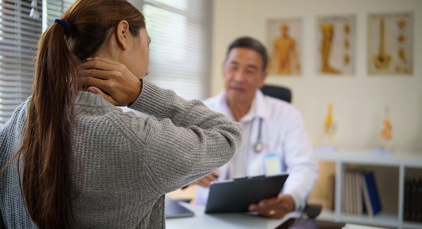 woman-holding-her-neck-while-talking-with-a-doctor-in-an-exam-room